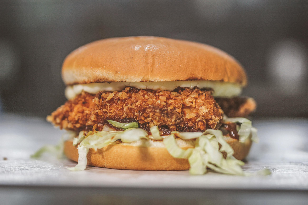 Burger au poulet croustillant avec de la salade.