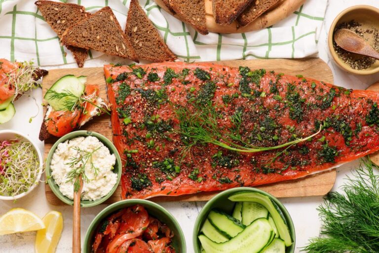 Filet de gravlax de saumon à l'aneth sur une planche avec pain et crudités.