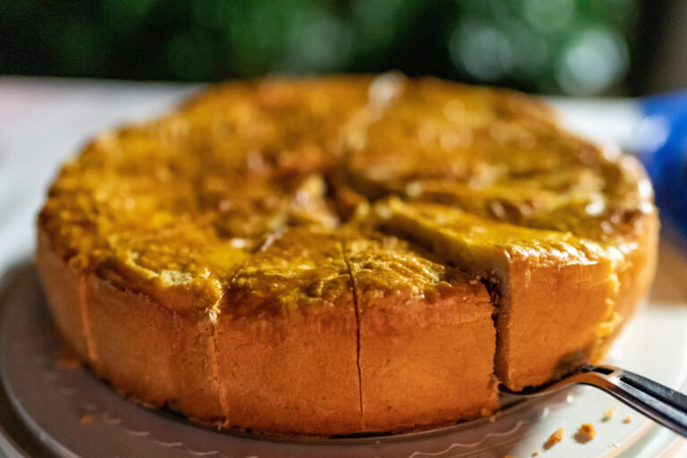 Kuchen doré et épais sur un plat, avec une part découpée.