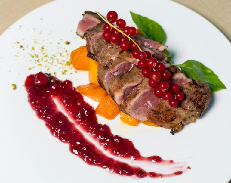 Magret de canard rosé, servi avec groseilles, abricots et coulis de fruits.