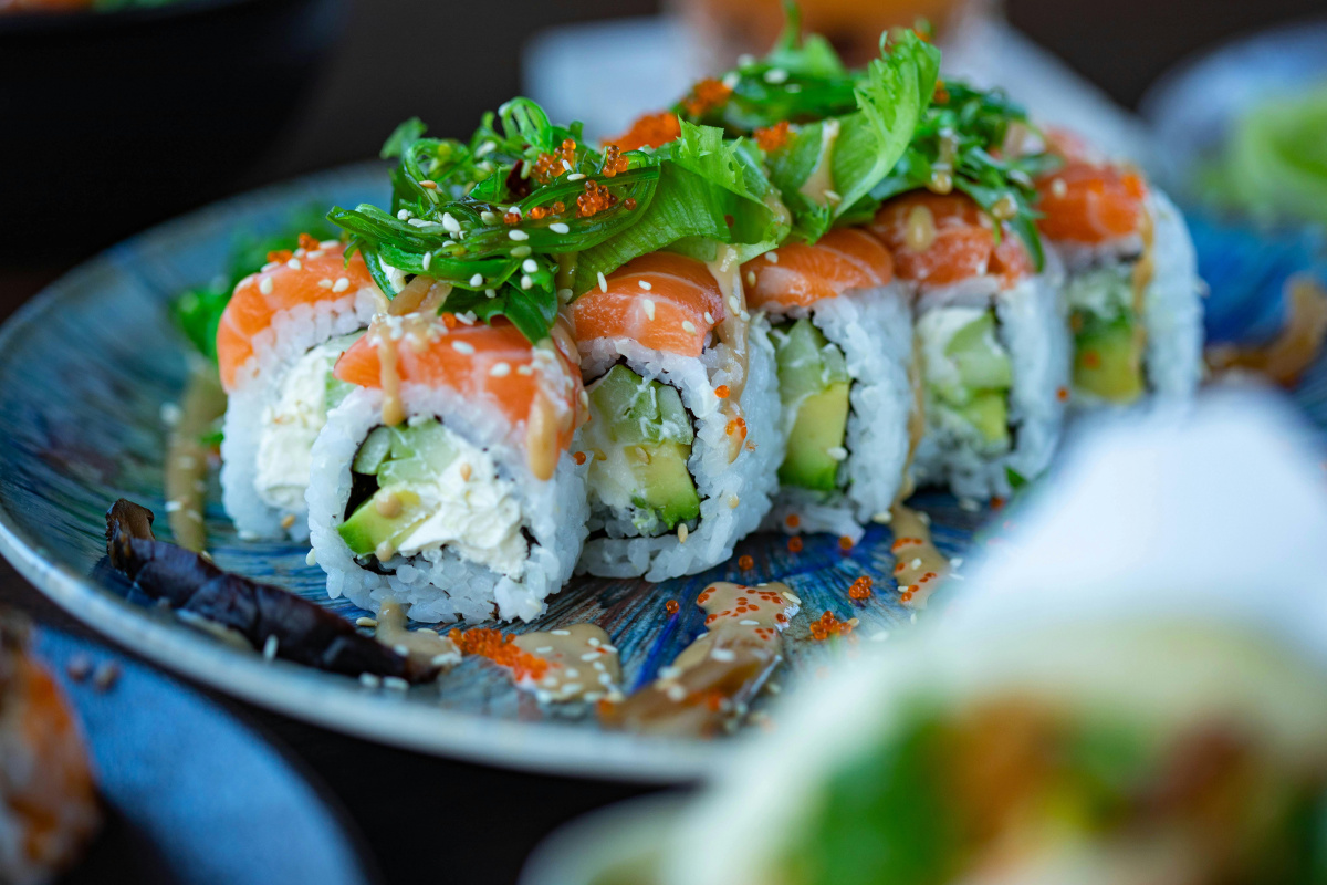 Makis californiens au saumon garnis de wakame et servis dans une assiette.