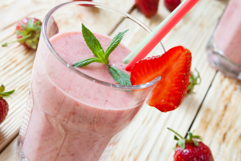 Milk-shake à la fraise servi dans un verre, garni de menthe et de fruits frais.