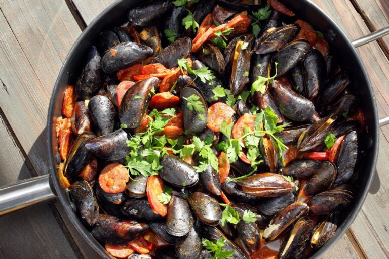 Poêle de moules au chorizo cuites et garnies de persil.