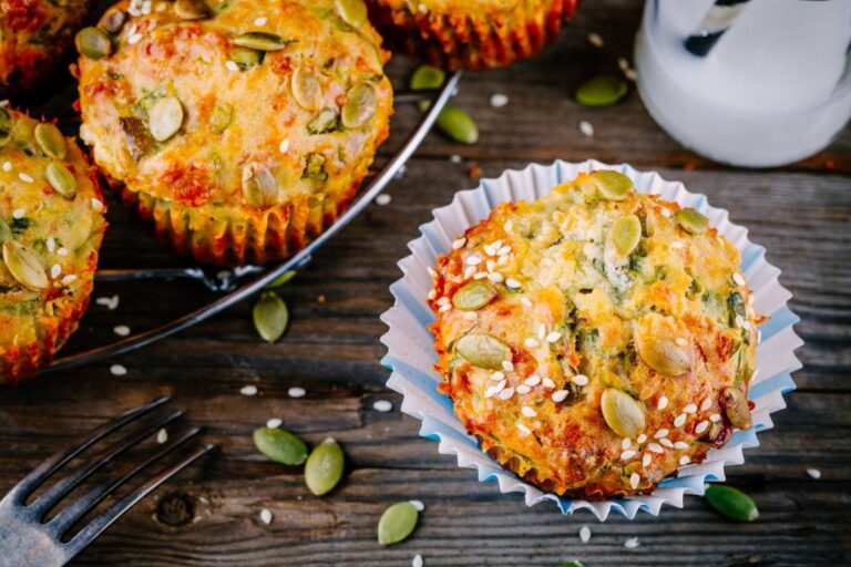 Muffins salés aux épinards, feta et graines sur une table rustique en bois.
