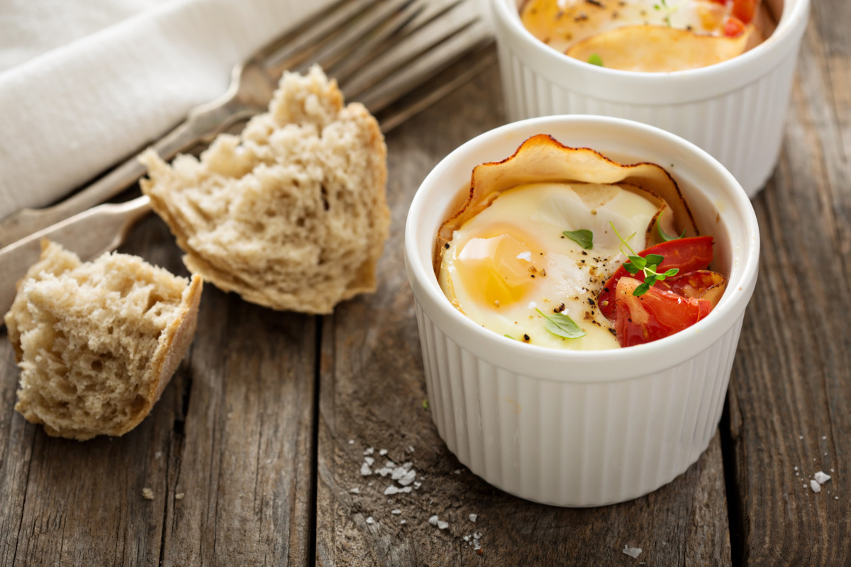 Œufs cocotte au jambon et tomate servis avec du pain.