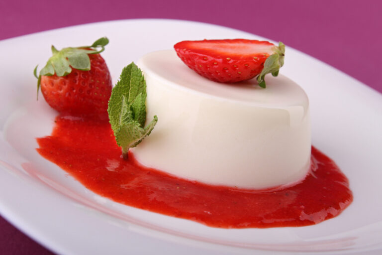 Panna cotta à la fraise servie avec coulis, fraises fraîches et menthe.