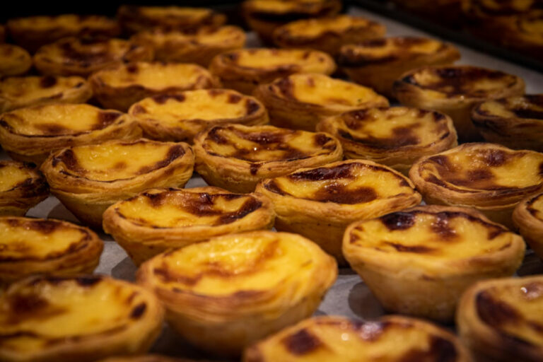 Pastéis de nata dorés et caramélisés sur une plaque.