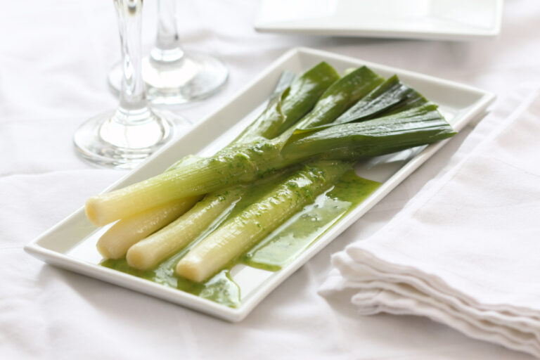 Poireaux cuits servis avec une vinaigrette verte aux herbes.