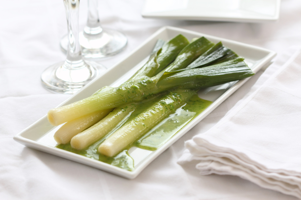 Poireaux cuits servis avec une vinaigrette verte aux herbes.