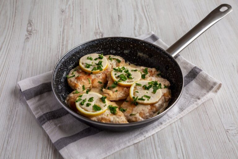Poêle de poulet crémeux au citron, garni de basilic et de rondelles de citron.