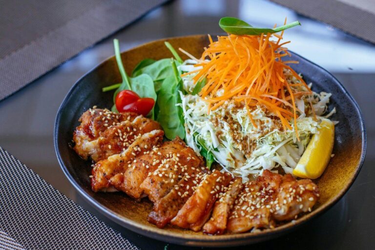 Poulet teriyaki tranché avec une salade de chou, carottes et épinards.