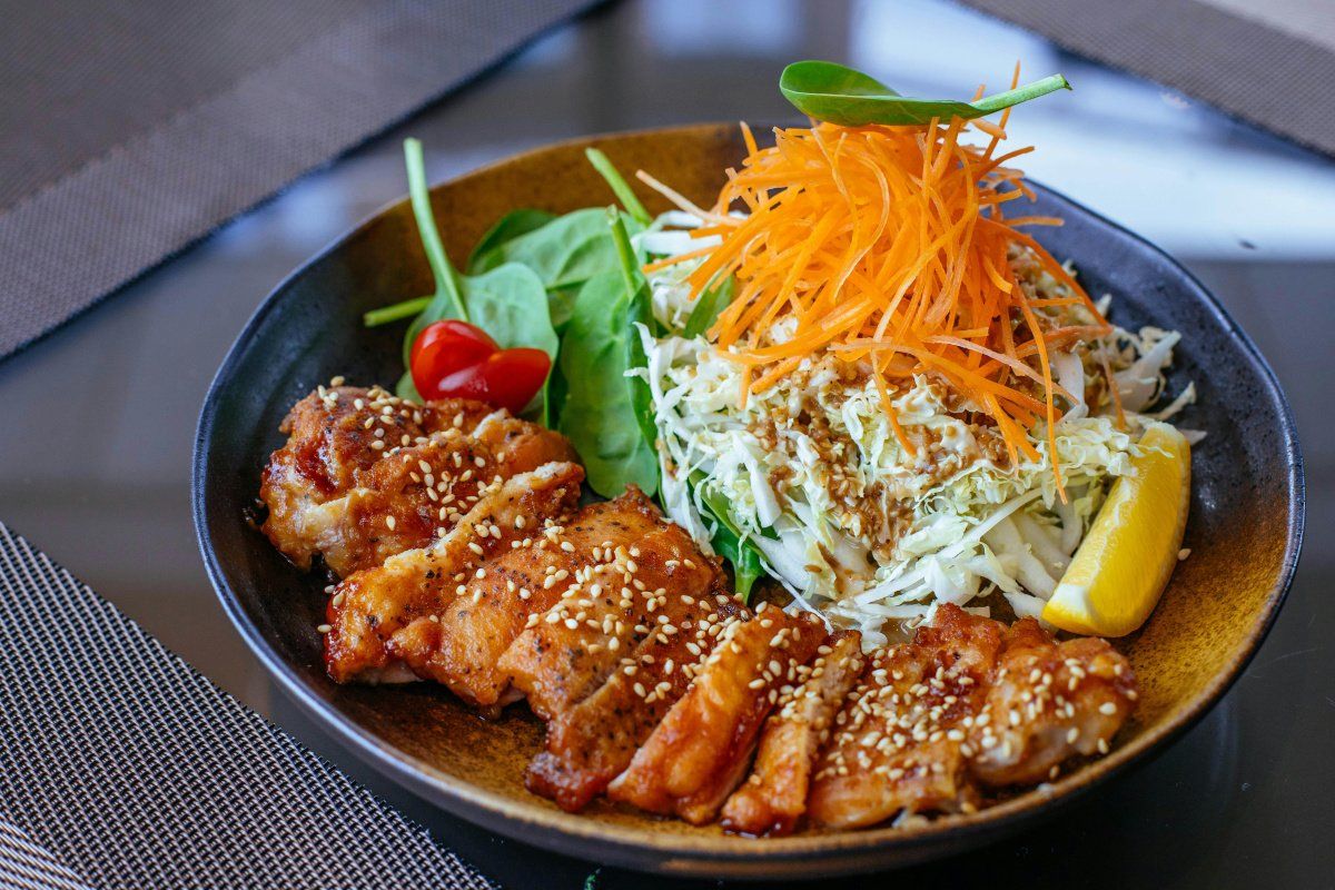 Poulet teriyaki tranch&eacute; avec une salade de chou, carottes et &eacute;pinards.