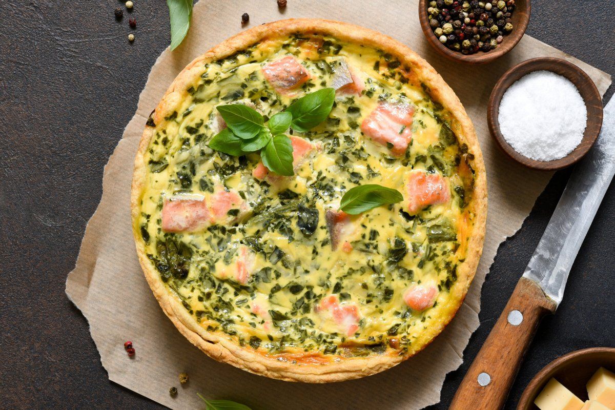 Quiche au saumon et blettes d&eacute;cor&eacute;e avec du basilic.