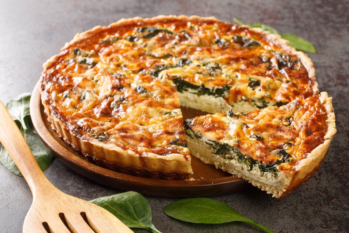 Quiche florentine dor&eacute;e aux &eacute;pinards, avec une part coup&eacute;e.