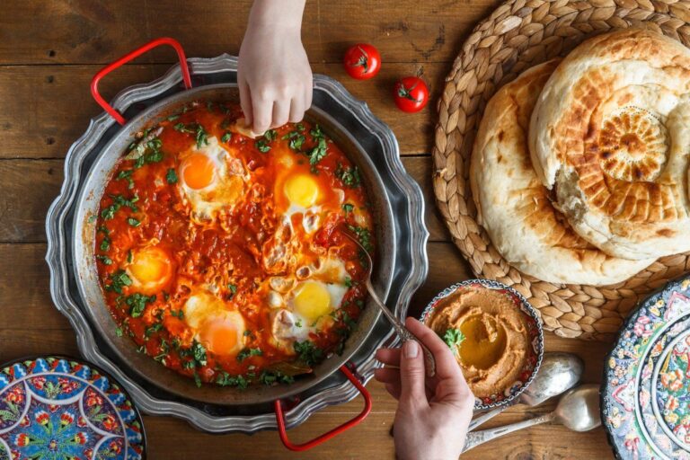Shakshuka partagé, servi avec du pain et du houmous.