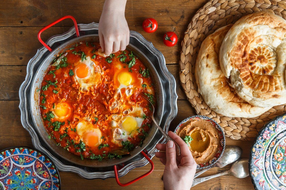 Shakshuka partag&eacute;, servi avec du pain et du houmous.
