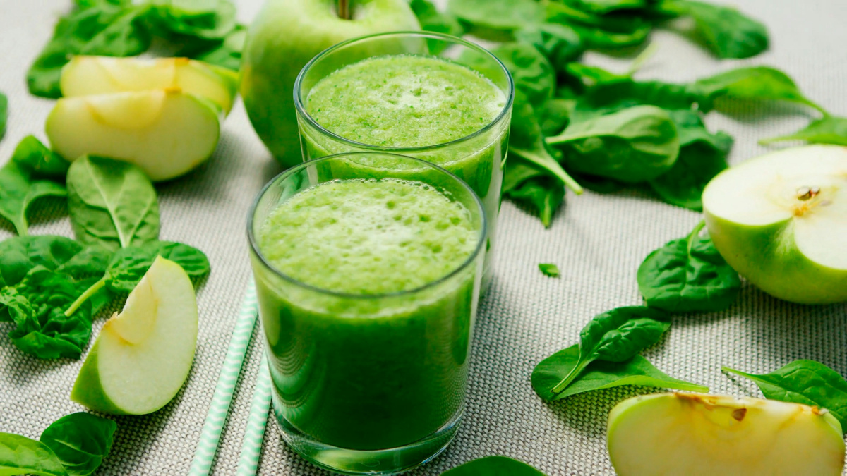 Smoothie vert frais entour&eacute;s de feuilles d'&eacute;pinards et de pommes vertes.