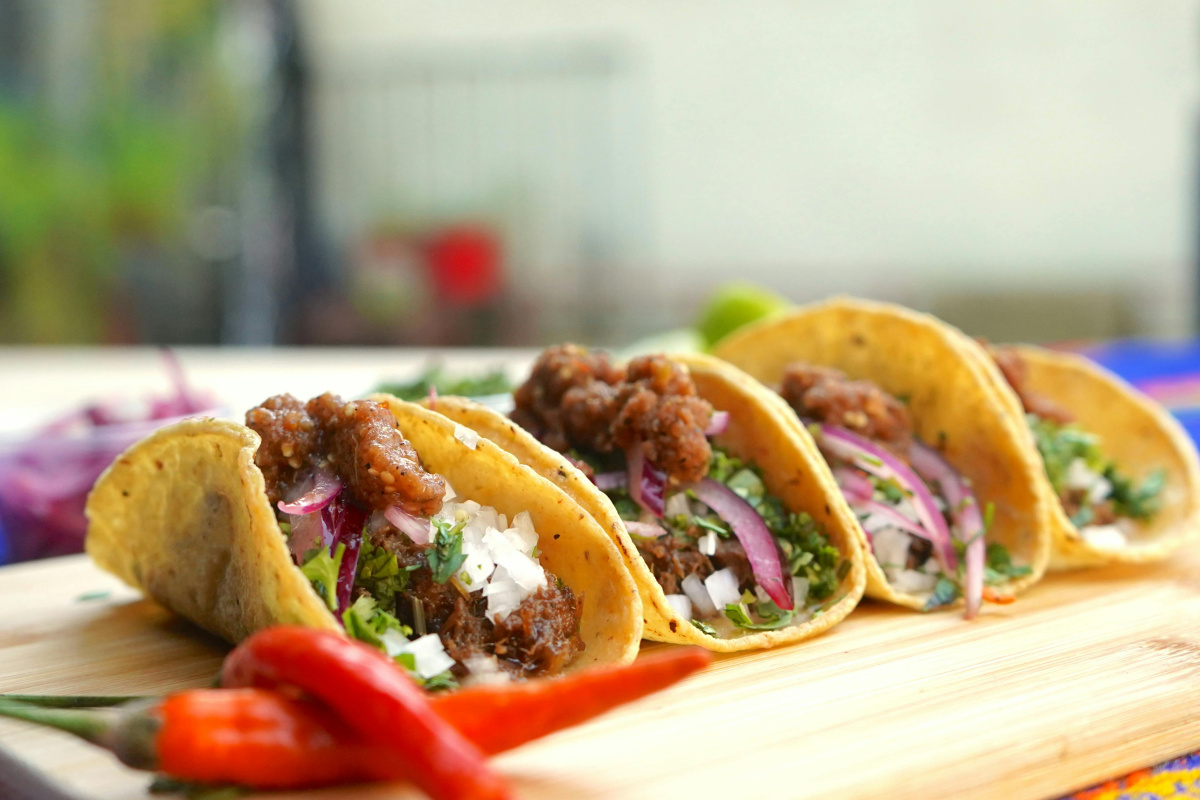 Tacos &agrave; la viande de b&oelig;uf et oignons servis sur une planche.