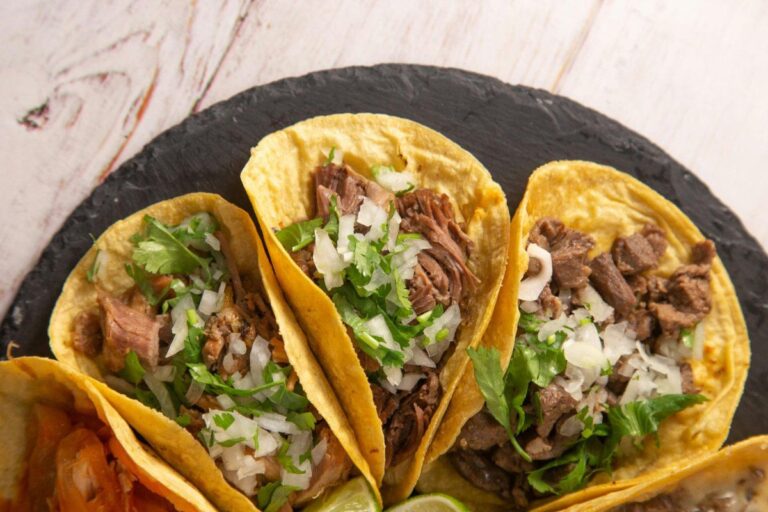 Gros plan sur des tacos au bœuf garnis d'oignon et de coriandre fraîche.