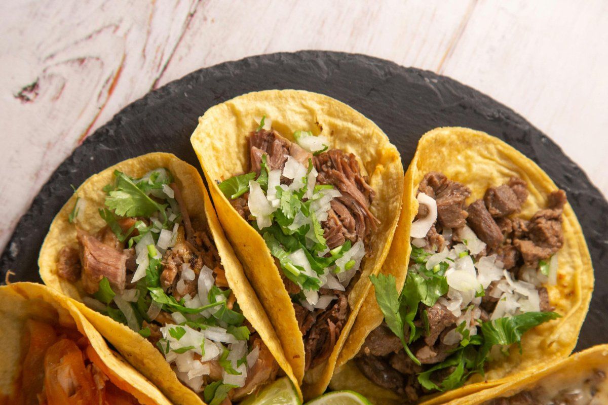 Gros plan sur des tacos au b&oelig;uf garnis d'oignon et de coriandre fra&icirc;che.