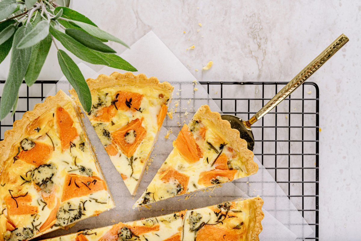 Tarte sal&eacute;e &agrave; la courge et au fromage bleu, coup&eacute;e en parts sur une grille.