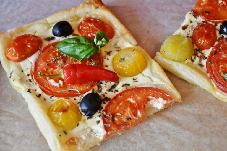 Deux parts de tarte feuilletée aux tomates, olives et basilic.
