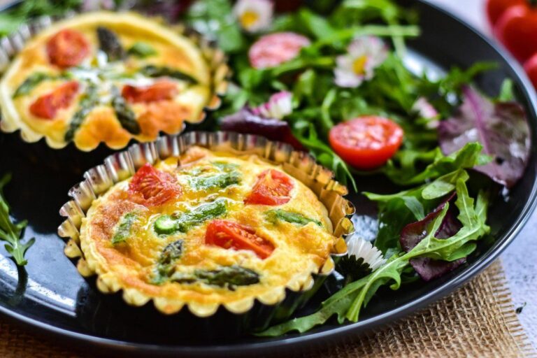 Tartelettes salées aux asperges et tomates servies avec une salade de roquette.