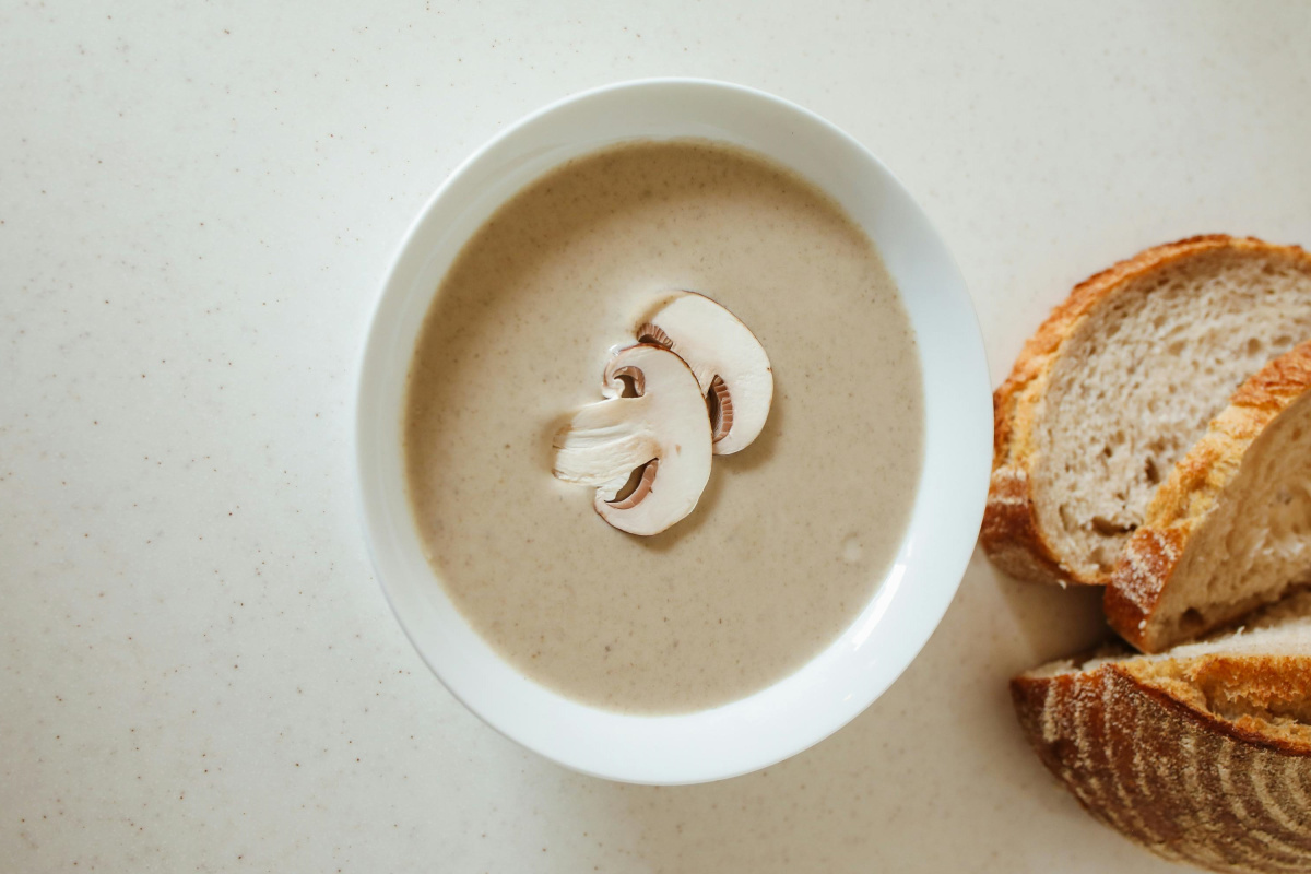 Bol de velout&eacute; de champignons, garni de lamelles, avec du pain.