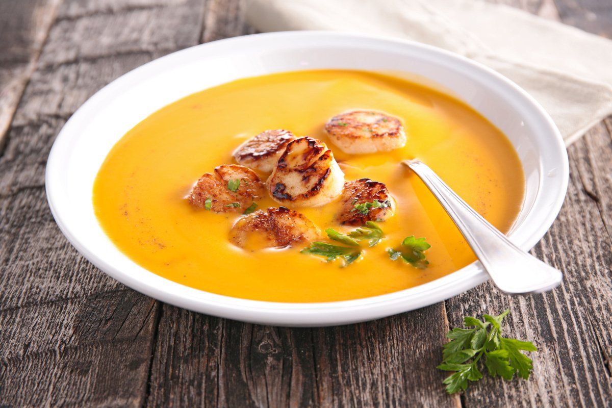 Velout&eacute; de potiron onctueux garni de noix de Saint-Jacques po&ecirc;l&eacute;es.