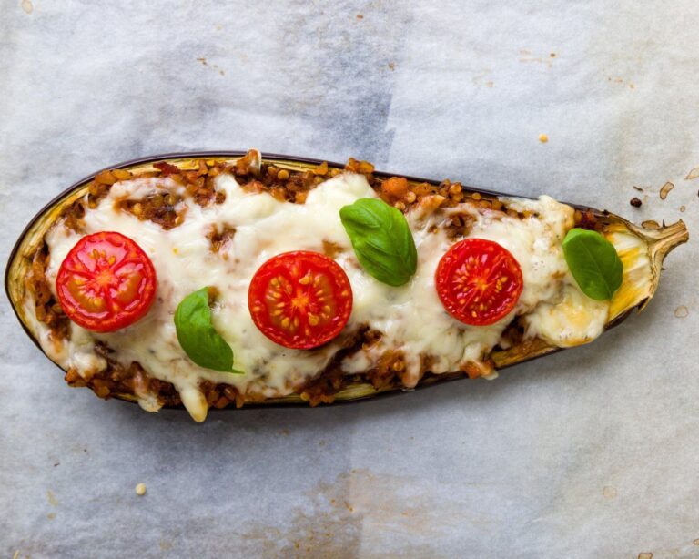 Aubergine farcie au boulgour gratinée, décorée de tomates cerises et de basilic frais.