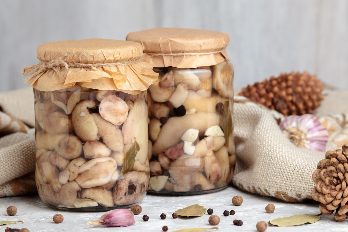 Bocaux en verre de champignons bolets marin&eacute;s avec de l'ail et des &eacute;pices.