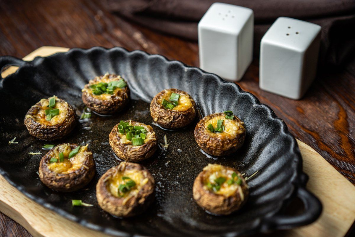 Champignons farcis au fromage gratiné et décorés de ciboule.