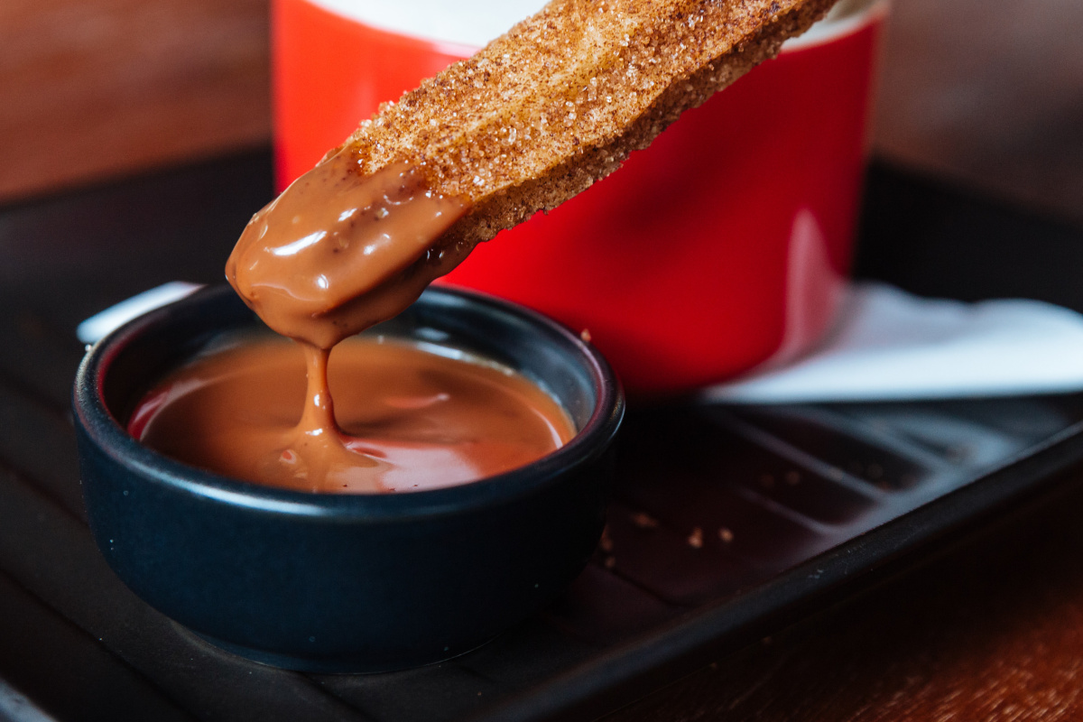 Churro enrob&eacute; de sucre tremp&eacute; dans une sauce au chocolat.