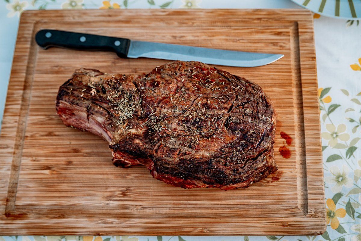 Cote de bœuf grillée aux herbes sur une planche à découper.