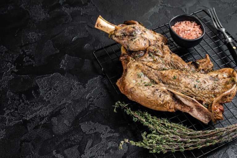 Épaule d'agneau rôtie aux herbes sur une grille avec thym et sel rose.
