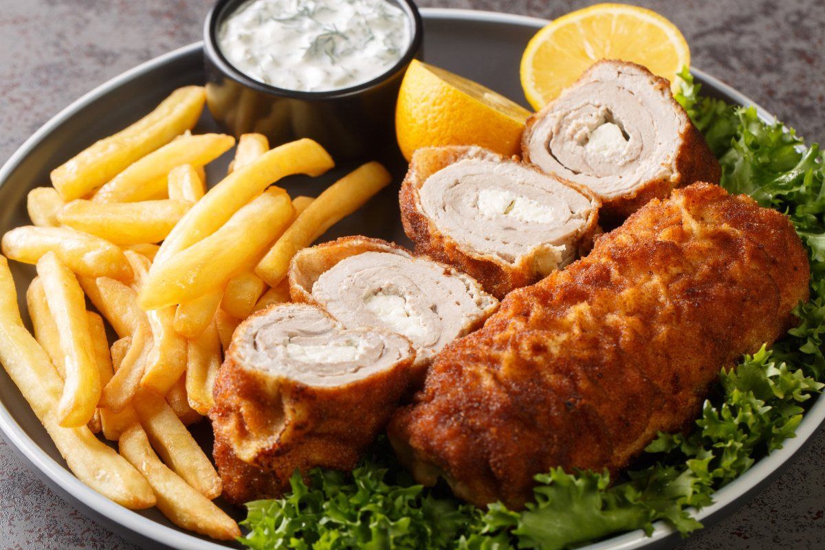 Schnitzel de Karageorge serbe roul&eacute; et pan&eacute;, servi avec des frites et une sauce.