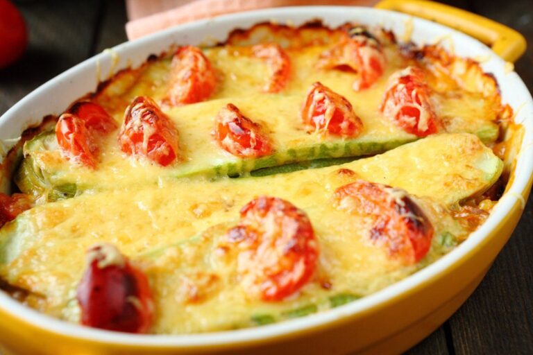 Gros plan sur un gratin de courgettes et tomates au fromage doré.