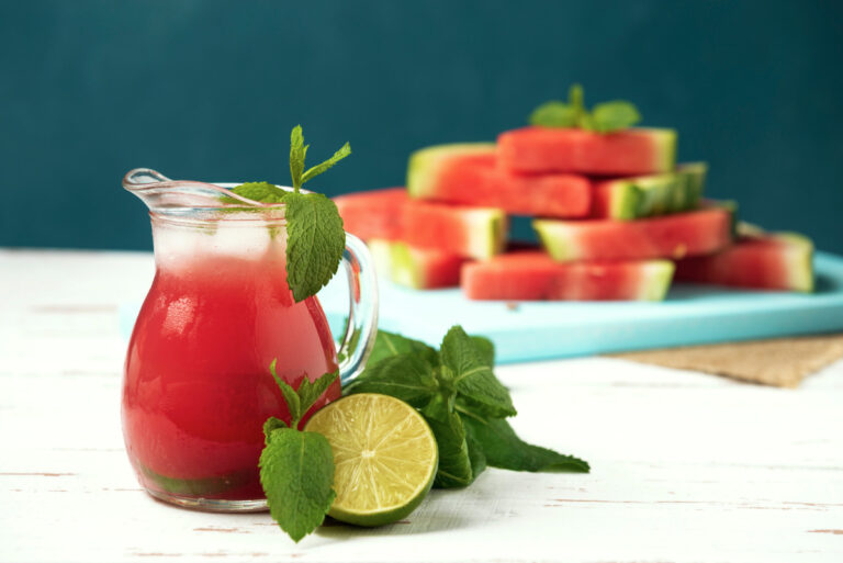 Pichet de jus de pastèque glacé décoré de menthe fraîche et citron vert.