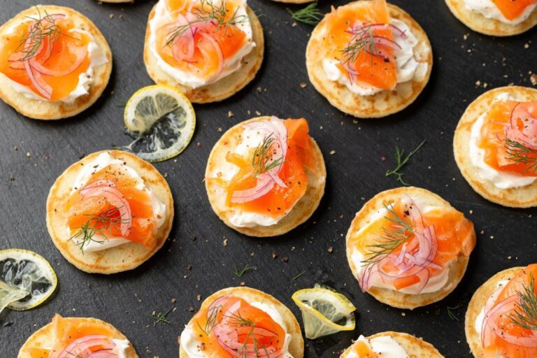 Mini blinis au saumon fumé et aneth sur une ardoise.