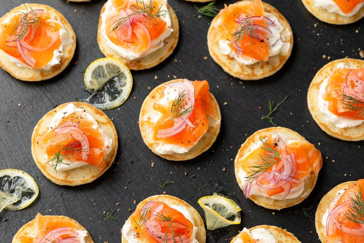 Mini blinis au saumon fum&eacute; et aneth sur une ardoise.