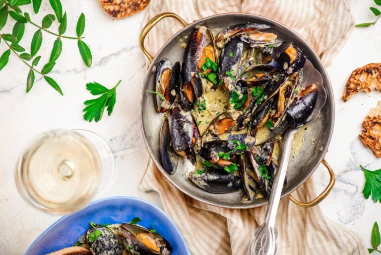 Plat de moules à la crème dans une poêle, servi avec du pain grillé.
