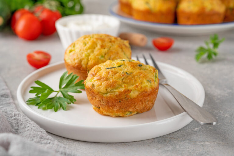 Deux muffins salés à la courgette sur une assiette blanche avec du persil.