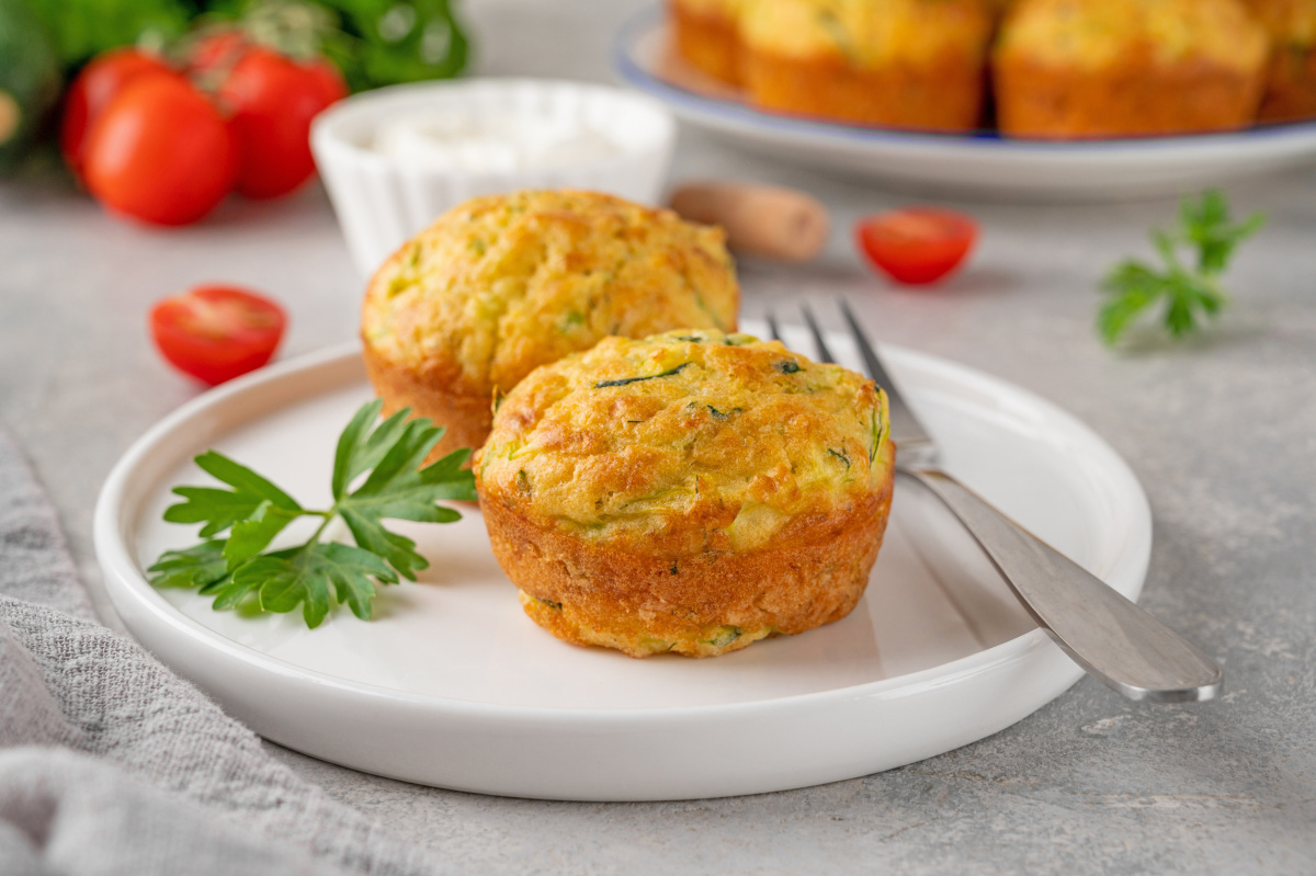 Deux muffins sal&eacute;s &agrave; la courgette sur une assiette blanche avec du persil.
