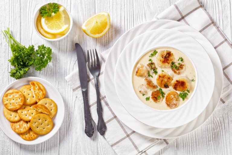 Plat de noix de Saint-Jacques poêlées dans une sauce crème, servi avec du persil.