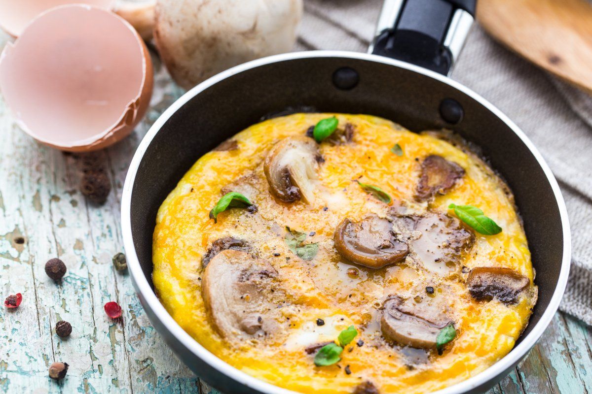 Omelette aux champignons dor&eacute;e, garnie de basilic et de poivre.