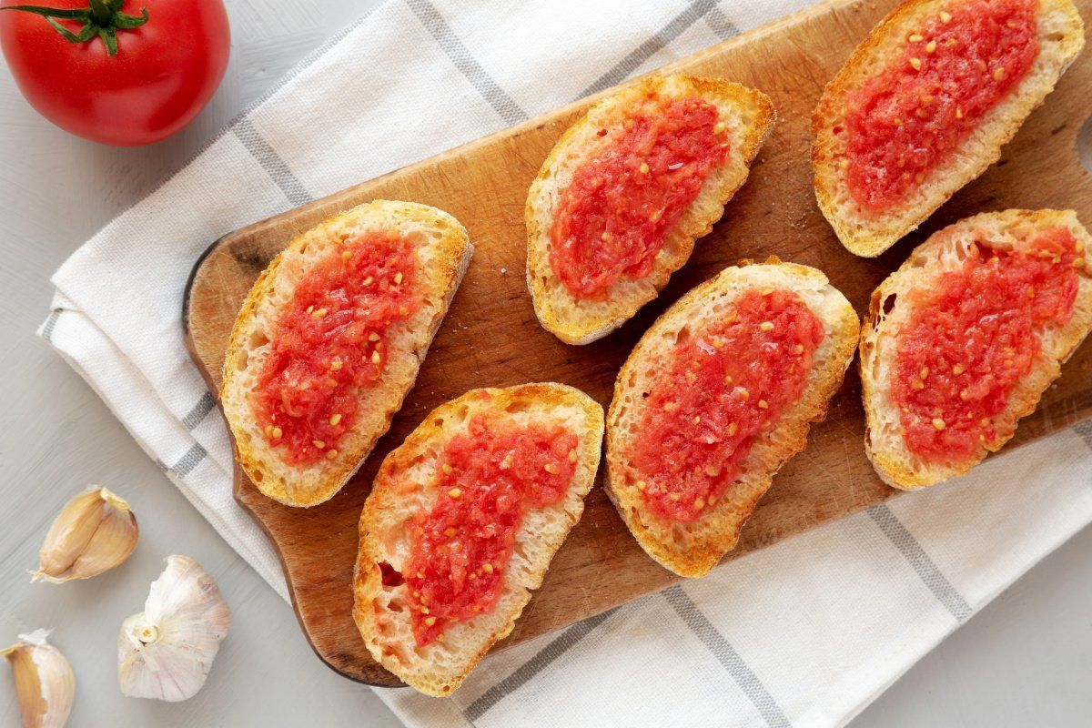 Pan con tomate maison servi sur une planche en bois.