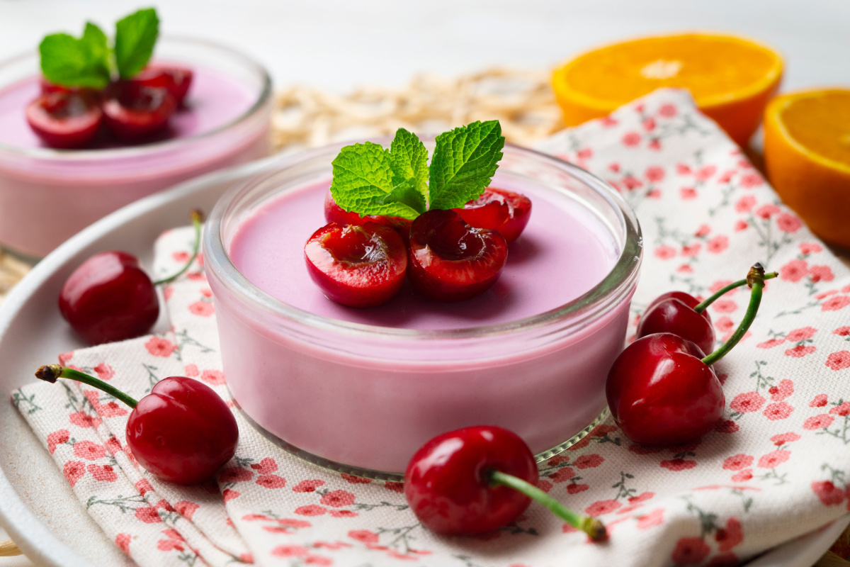 Panna cotta rose &agrave; la cerise dans un verre, garnie de fruits frais.