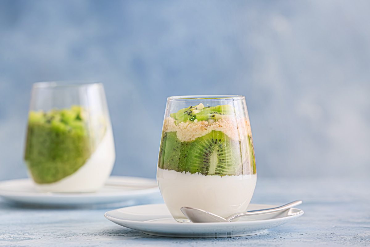 Verrine de panna cotta cr&eacute;meuse avec des couches de kiwi frais et crumble.