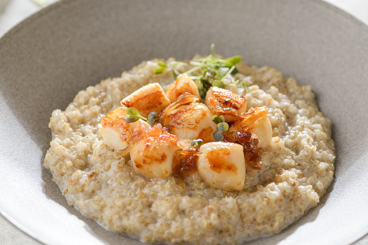 P&eacute;toncles snack&eacute;es sur un lit de quinoa cr&eacute;meux, garnis de micropousses vertes.