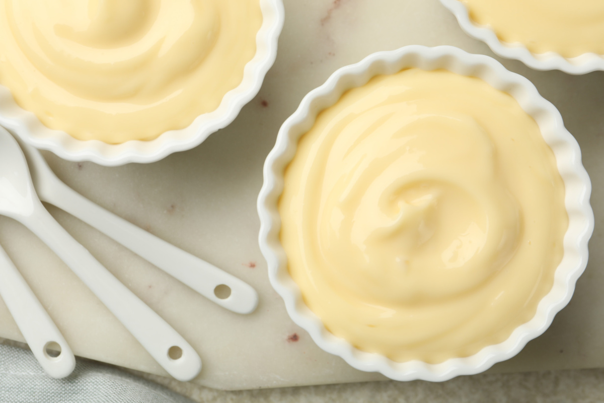 Vue de dessus de ramequins blancs remplis de pudding cr&eacute;meux &agrave; la vanille.